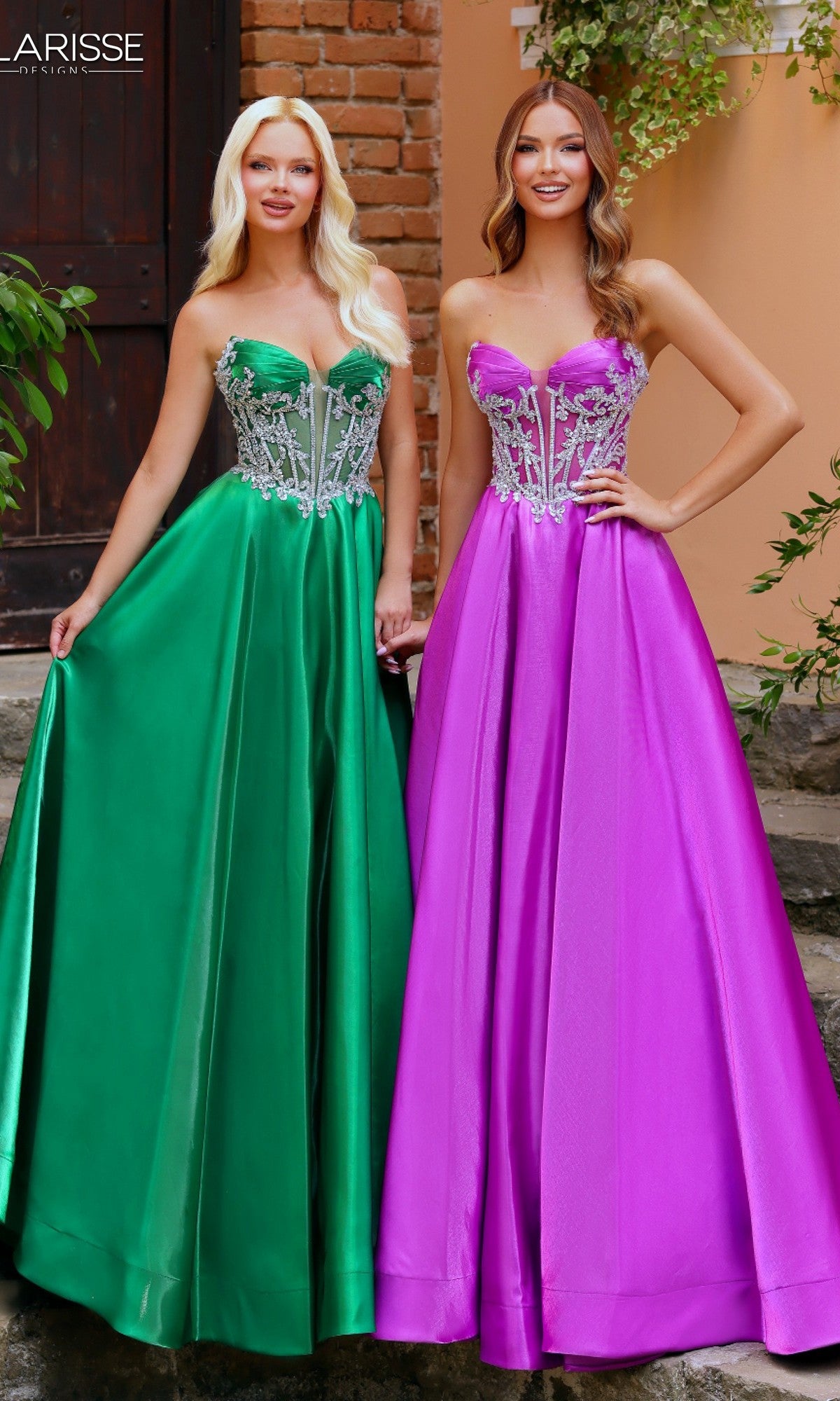 Two women stand outdoors by a peach wall, each wearing the Clarisse Designs 62140 prom ball gown with a beaded corset bodice—one in green liquid satin, the other in rich purple.